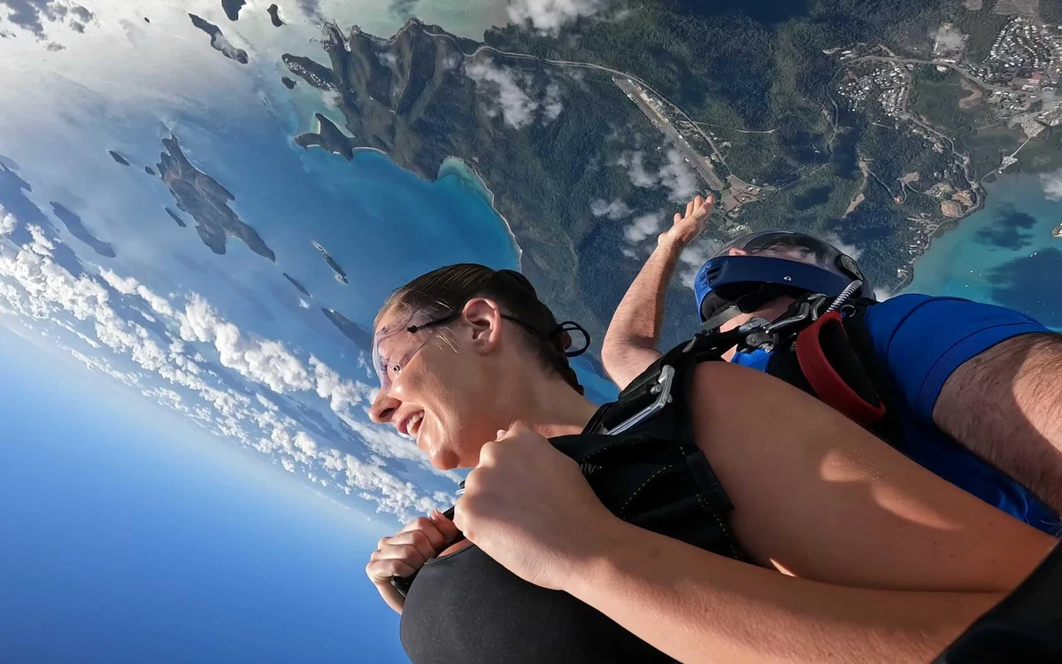 A tandem pair in freefall above the coast, the islands and the turquoise shallows