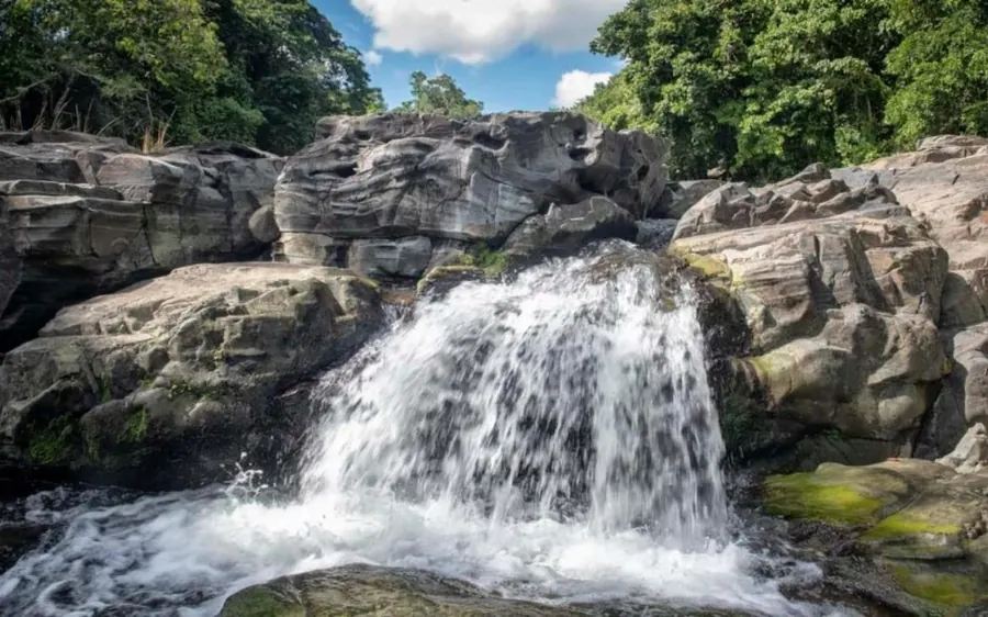 Ein Wasserfall über grauem Fels in ein flaches Becken