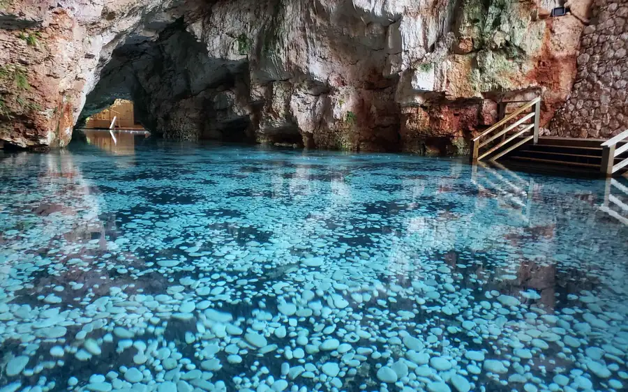 Türkisfarbenes Wasser in einer Cenote-Höhle, mit Stufen hinunter zum Pool